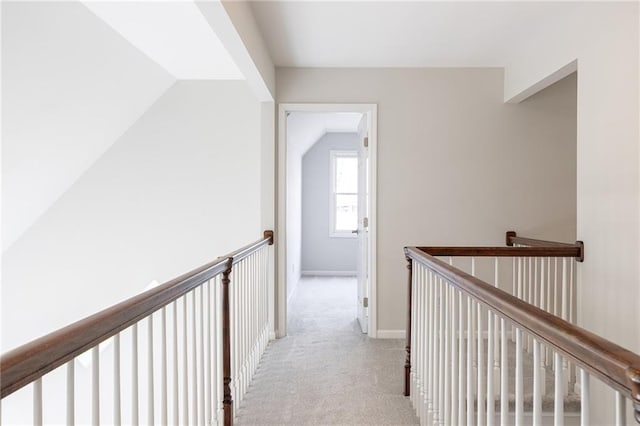 hallway featuring an upstairs landing, carpet flooring, baseboards, and vaulted ceiling