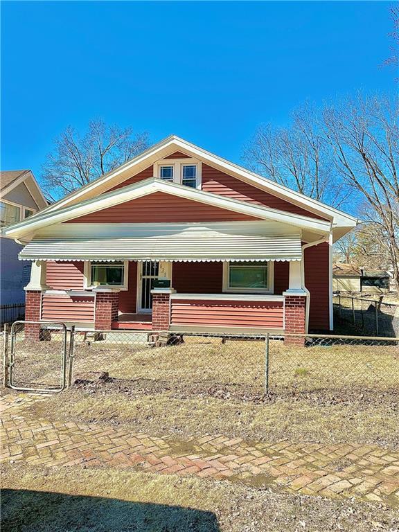 bungalow-style house featuring a porch, a fenced front yard, and a gate