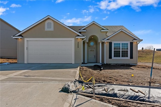 view of front of property with a garage, a shingled roof, concrete driveway, and stucco siding