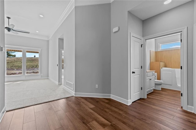 foyer entrance featuring visible vents, baseboards, ceiling fan, ornamental molding, and wood finished floors