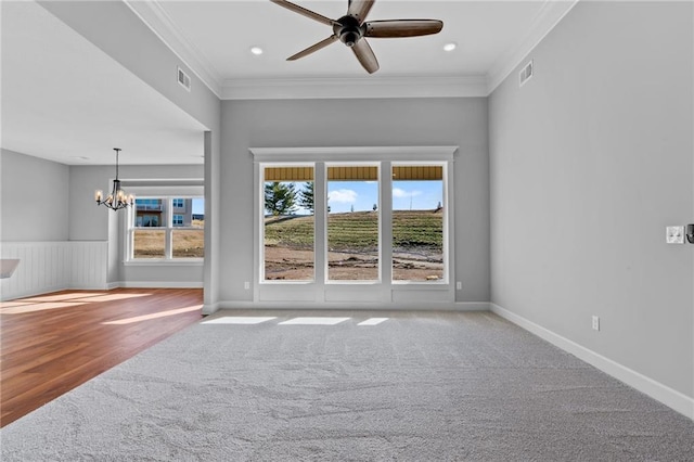 empty room featuring plenty of natural light, ceiling fan with notable chandelier, visible vents, and ornamental molding