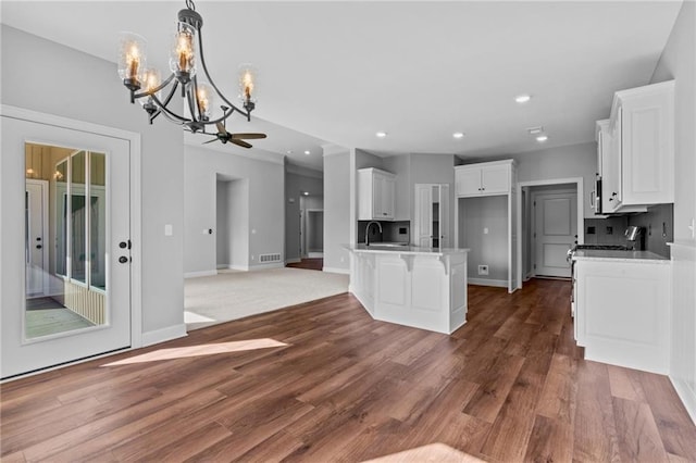 kitchen with a breakfast bar, open floor plan, wood finished floors, white cabinetry, and a sink