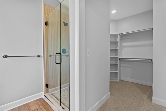 bathroom featuring a shower stall, baseboards, and a walk in closet