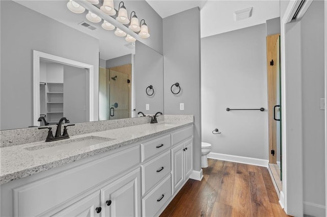 2409 Merlot Pl, Excelsior Springs, MO 64024 - bathroom featuring a stall shower, double vanity, wood finished floors, and a spacious closet