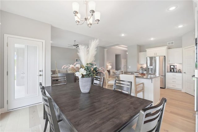 dining room featuring light wood finished floors, ceiling fan with notable chandelier, visible vents, and recessed lighting
