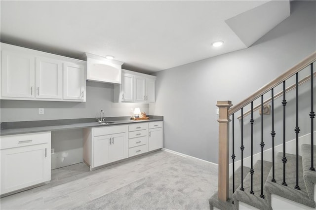 kitchen with baseboards, light wood-type flooring, recessed lighting, white cabinetry, and a sink