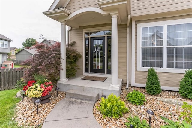 property entrance featuring covered porch and fence