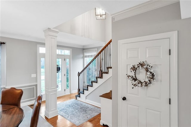 entryway featuring ornamental molding, decorative columns, and wood finished floors