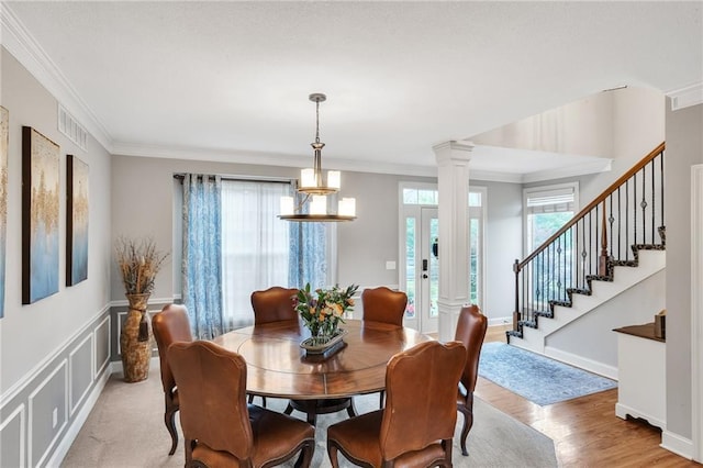 dining room with decorative columns, baseboards, ornamental molding, stairs, and light wood-type flooring