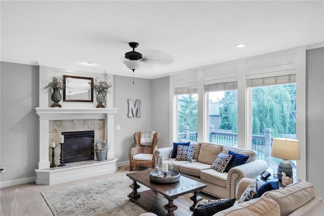 living area with baseboards, a ceiling fan, crown molding, carpet floors, and a fireplace