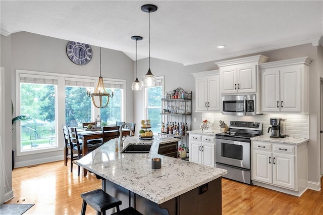 kitchen with appliances with stainless steel finishes, white cabinetry, backsplash, and a kitchen breakfast bar