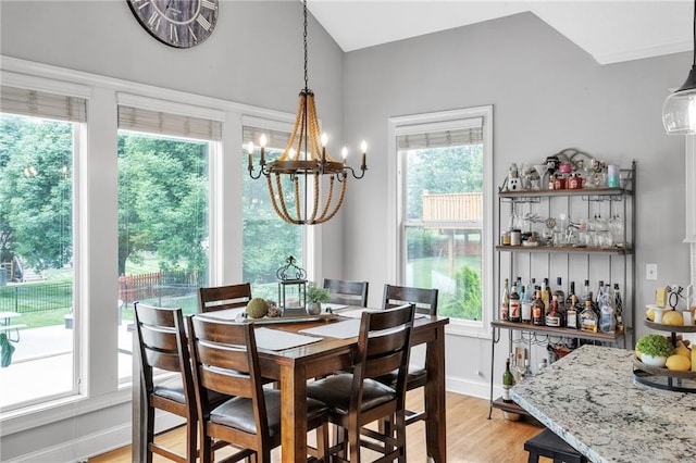 dining space with light wood-type flooring, baseboards, a chandelier, and a dry bar