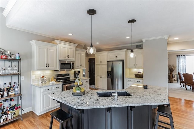 kitchen featuring light wood finished floors, a kitchen bar, white cabinetry, and stainless steel appliances