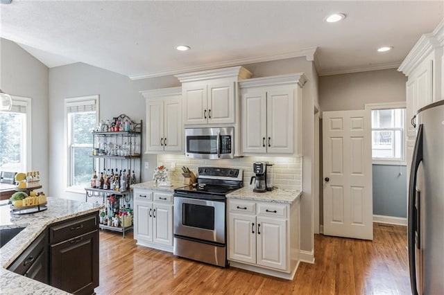 kitchen featuring stainless steel appliances, white cabinets, and tasteful backsplash