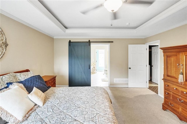 carpeted bedroom with a tray ceiling, visible vents, connected bathroom, and a barn door