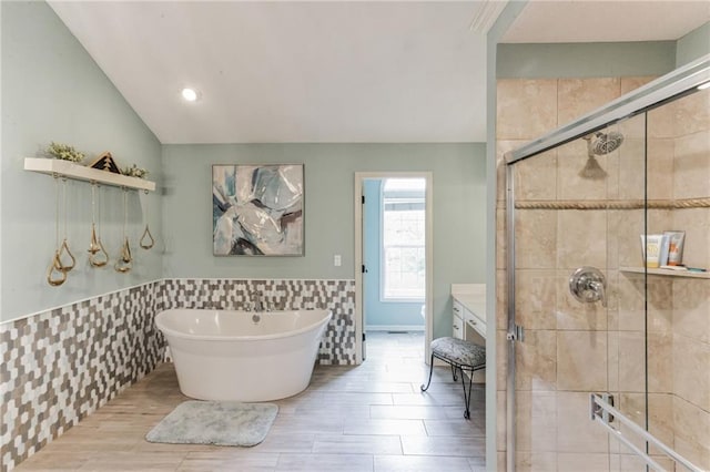 full bath with lofted ceiling, a freestanding bath, a shower stall, and tile walls