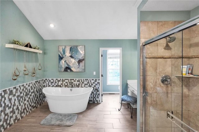 bathroom with a stall shower, a freestanding tub, lofted ceiling, and tile walls