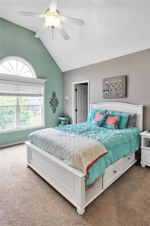 carpeted bedroom with vaulted ceiling and a ceiling fan