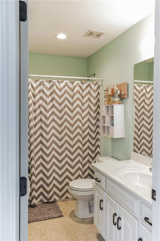 bathroom featuring visible vents, a shower with shower curtain, toilet, vanity, and tile patterned floors