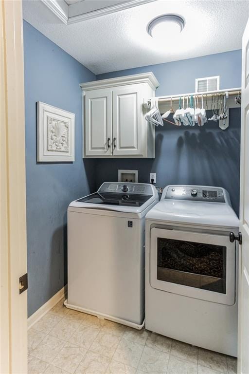 clothes washing area with cabinet space, a textured ceiling, visible vents, and washer and dryer