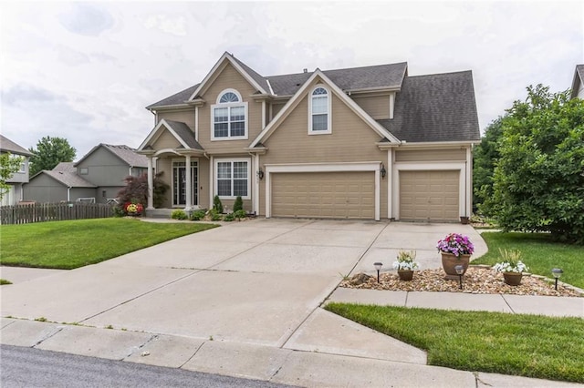 view of front facade with a garage, a shingled roof, concrete driveway, fence, and a front yard