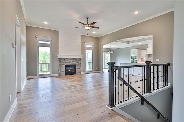 living room featuring light wood-style floors, a wealth of natural light, a stone fireplace, and baseboards