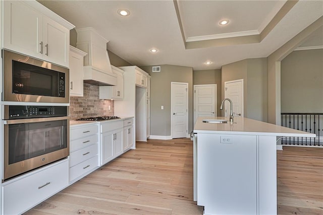 kitchen featuring stainless steel appliances, light wood-type flooring, a sink, and light countertops