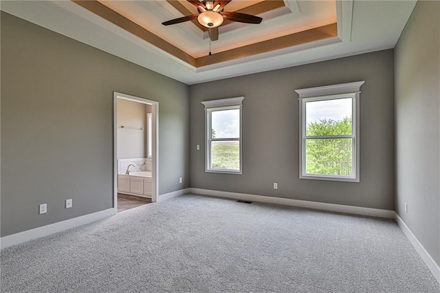 interior space featuring a tray ceiling, carpet, a ceiling fan, and baseboards