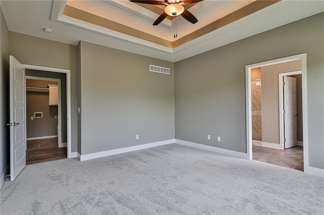 unfurnished bedroom with carpet floors, a raised ceiling, and visible vents