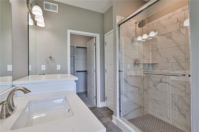 bathroom featuring visible vents, a spacious closet, a stall shower, vanity, and tile patterned floors