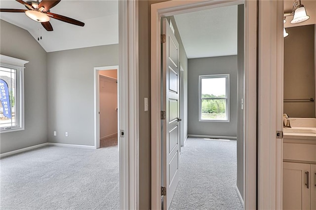 interior space featuring a ceiling fan, lofted ceiling, vanity, and baseboards