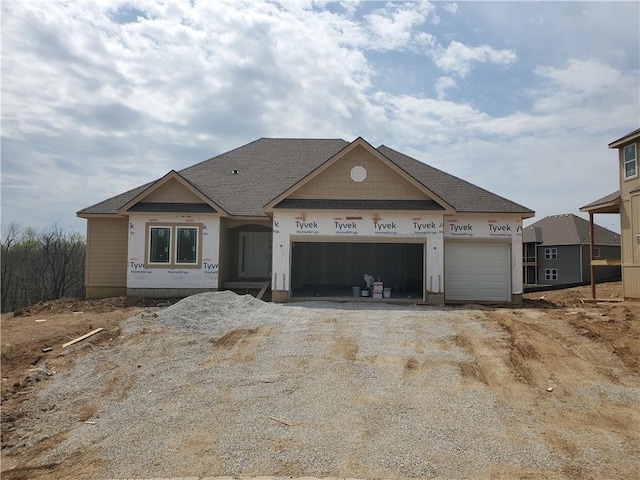 unfinished property with an attached garage, driveway, and roof with shingles