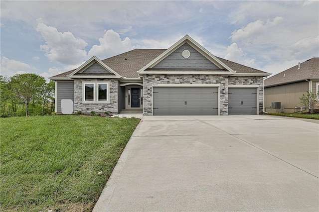 craftsman-style home with concrete driveway, stone siding, an attached garage, a front yard, and a shingled roof