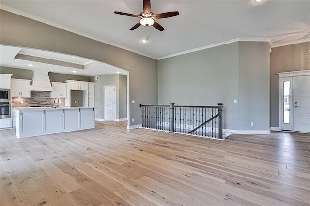 unfurnished living room with baseboards, a ceiling fan, light wood-style floors, crown molding, and recessed lighting