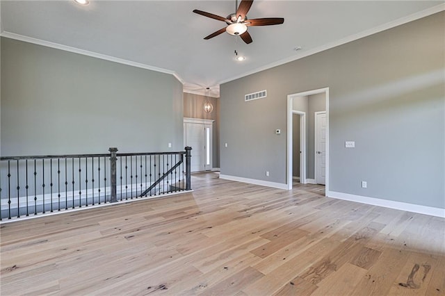 empty room featuring wood finished floors, ceiling fan, ornamental molding, and visible vents