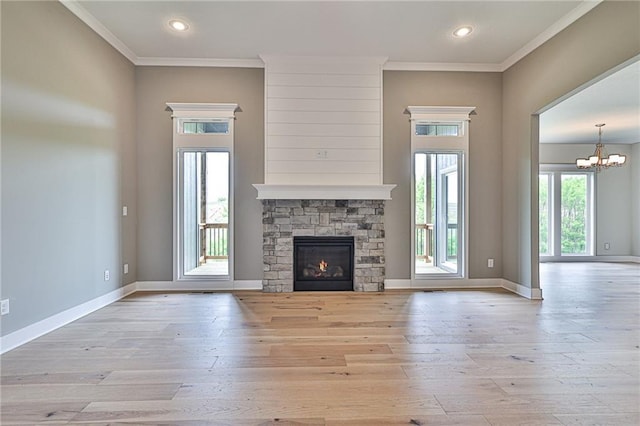 unfurnished living room featuring an inviting chandelier, light wood finished floors, a stone fireplace, and ornamental molding