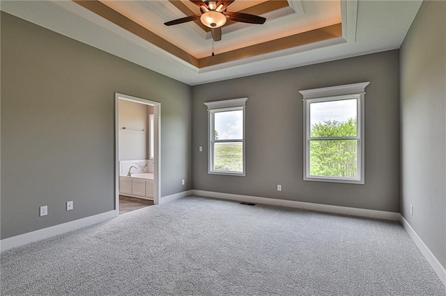 carpeted spare room featuring a tray ceiling, baseboards, and ceiling fan