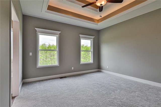 carpeted spare room with ceiling fan, baseboards, visible vents, and a raised ceiling