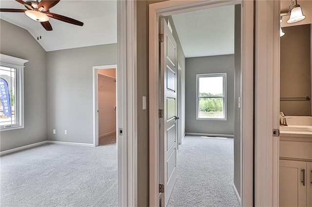 interior space featuring vanity, baseboards, a ceiling fan, and lofted ceiling