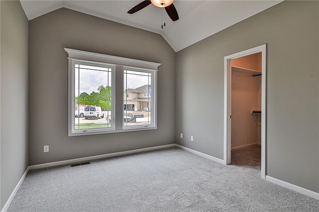 carpeted empty room with visible vents, baseboards, a ceiling fan, and lofted ceiling
