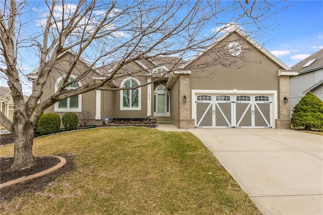 view of front of home featuring brick siding, a front lawn, stucco siding, a garage, and driveway