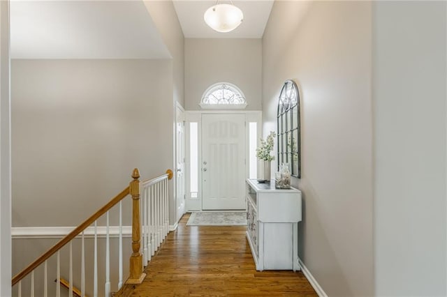 foyer with baseboards, a towering ceiling, and wood finished floors