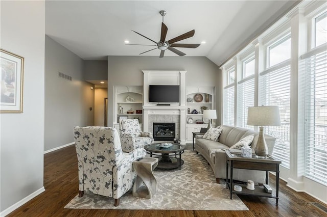 living room featuring visible vents, a ceiling fan, a fireplace, baseboards, and dark wood-style flooring