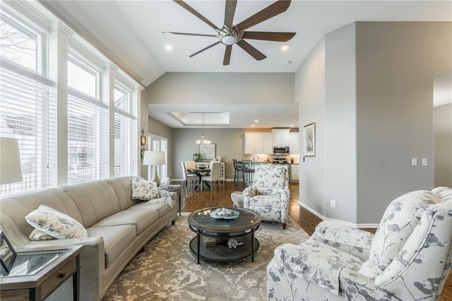 living room featuring a ceiling fan, wood finished floors, baseboards, a tray ceiling, and recessed lighting