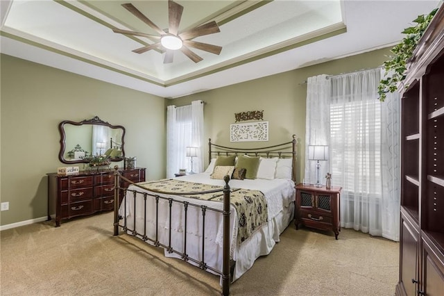 bedroom featuring light carpet, ceiling fan, a raised ceiling, and baseboards