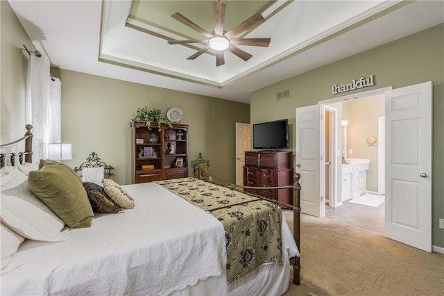 bedroom with visible vents, ensuite bath, carpet flooring, a raised ceiling, and ceiling fan