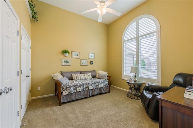 sitting room featuring light colored carpet, a ceiling fan, and baseboards