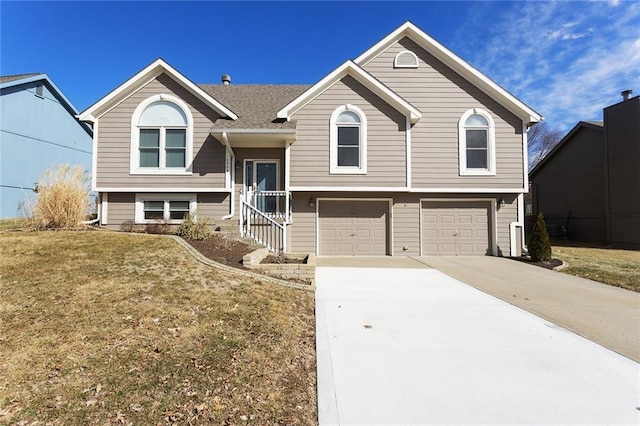 bi-level home with a front lawn, concrete driveway, and an attached garage