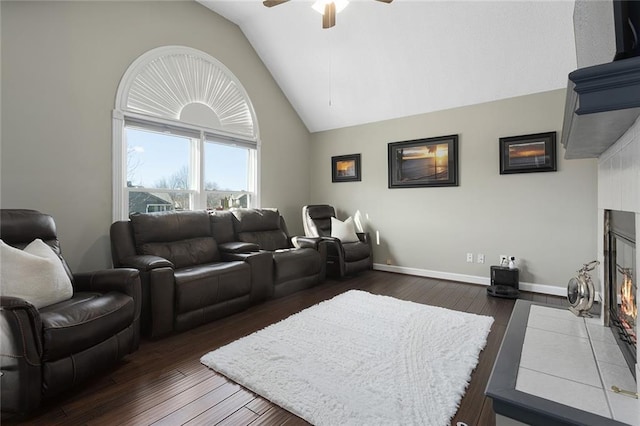 home theater room with high vaulted ceiling, dark wood-style floors, baseboards, and a tiled fireplace