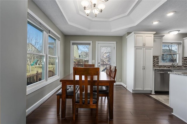 dining area featuring baseboards, a tray ceiling, dark wood-type flooring, and an inviting chandelier